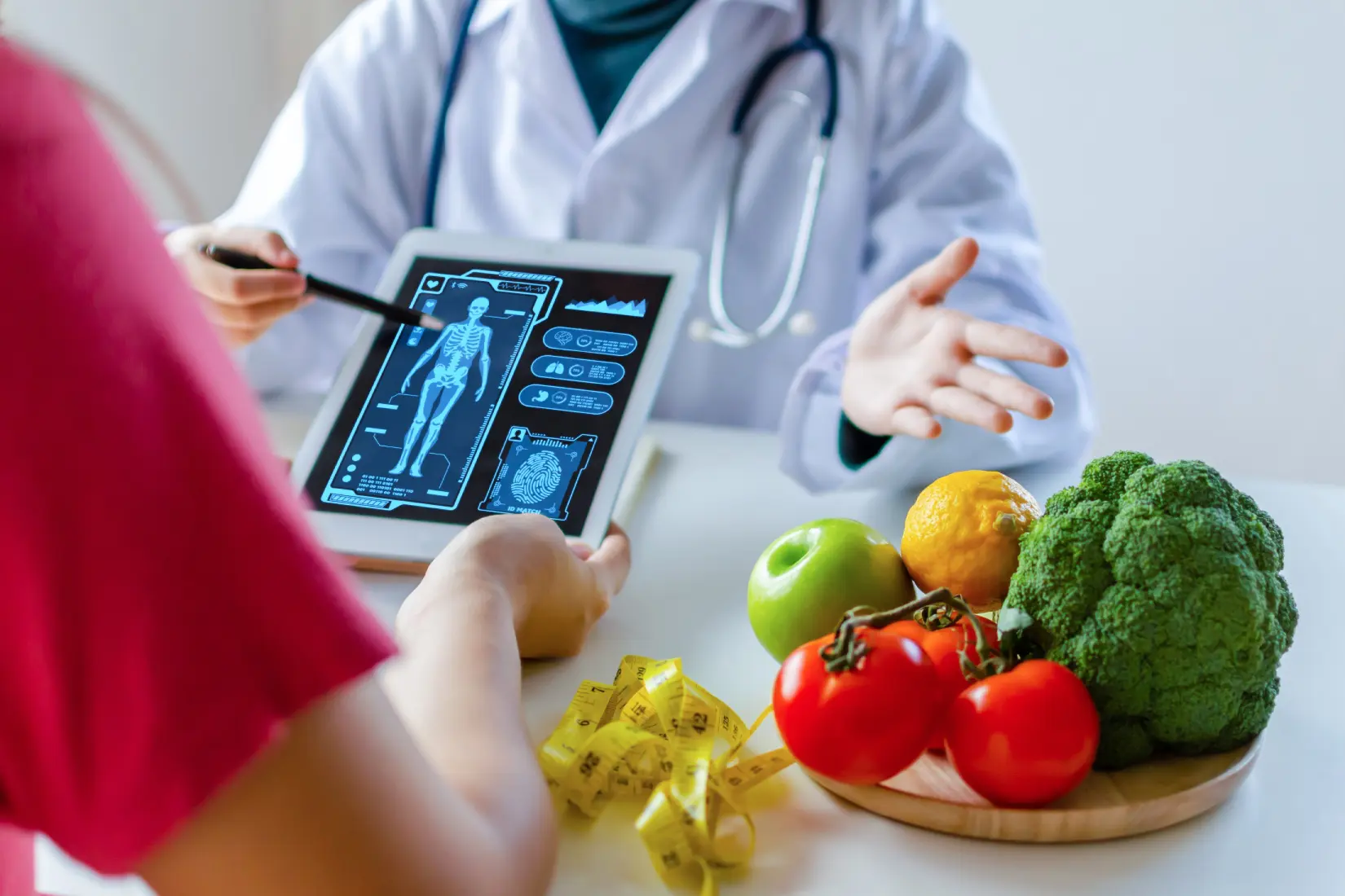 A doctor shows a digital X-ray on a tablet to a patient. Nearby, there's a plate with fruits and vegetables and a measuring tape, suggesting a discussion about health or diet.